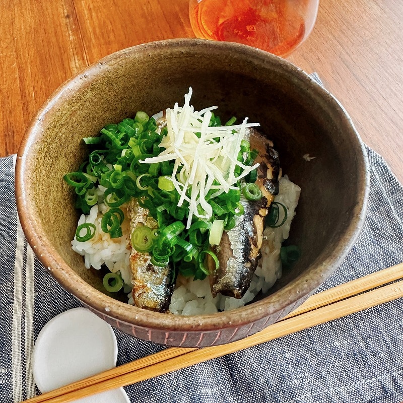 ごはんとイワシとネギが入った丼とロゼワインがテーブルに載っている